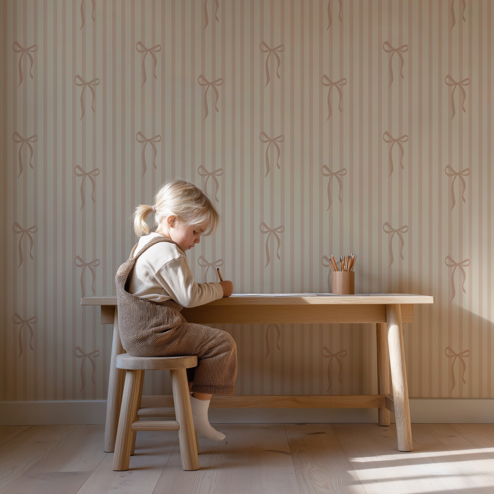 Peuter die aan een houten tafeltje tekent in de kinderkamer, met zacht gestreept behang met strikjes en warme natuurlijke tinten.