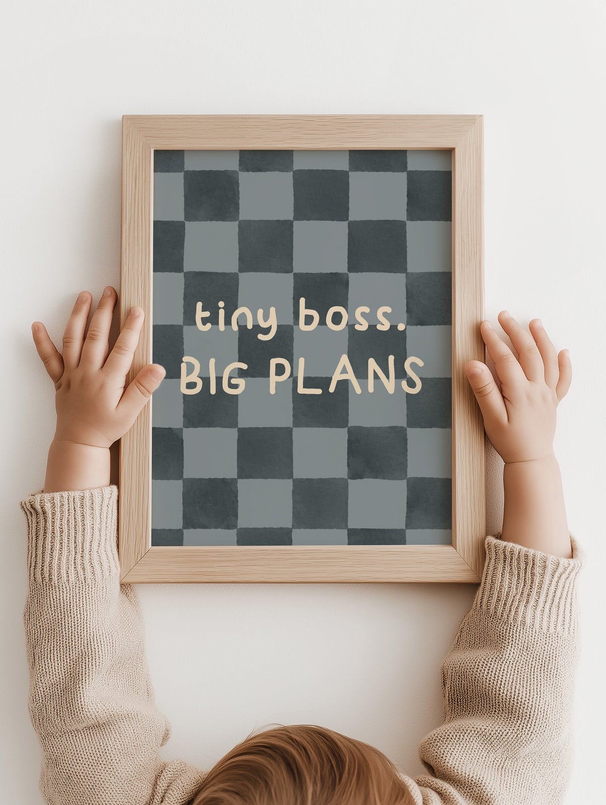 Kinderhanden houden de Tiny Boss, Big Plans poster in een houten lijst