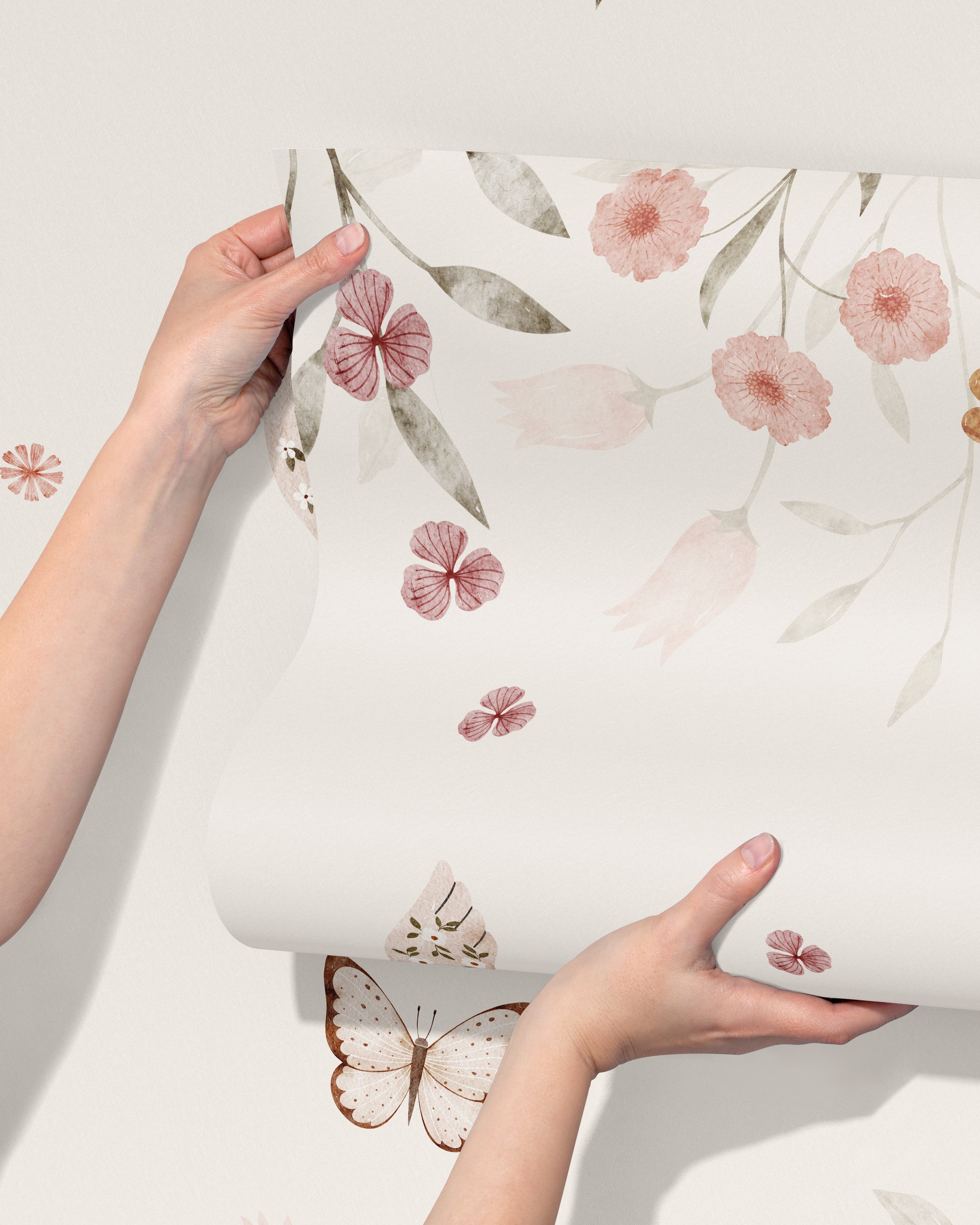 Handen die zacht bloemenbehang voor de kinderkamer aanbrengen met subtiele bloesems, bladeren en vlinders in lichte, rustige tinten.