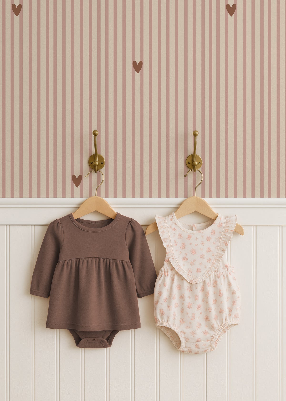 Roze gestreept hartjesbehang boven witte lambrisering met kinderjurkjes aan haakjes