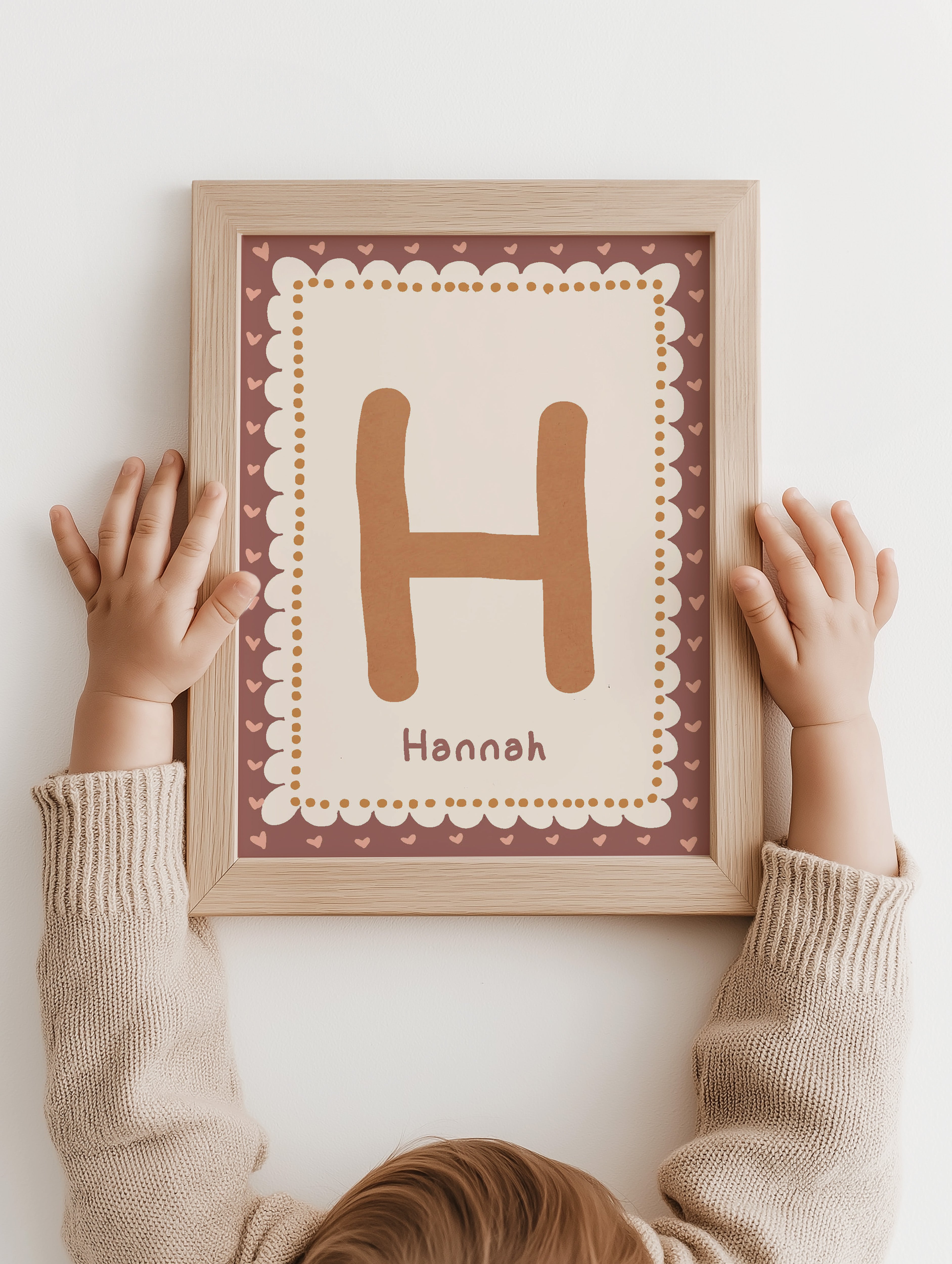 Kind houdt ingelijste naamposter met beginletter en persoonlijke naam vast